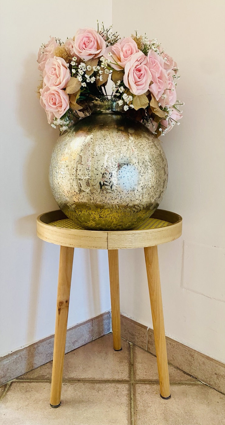 Vase argenté garni de roses poudrées sur une sellette en bois